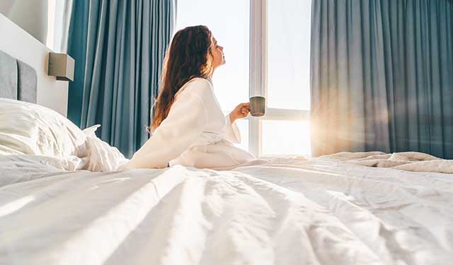 woman sitting on bed with coffee cup.